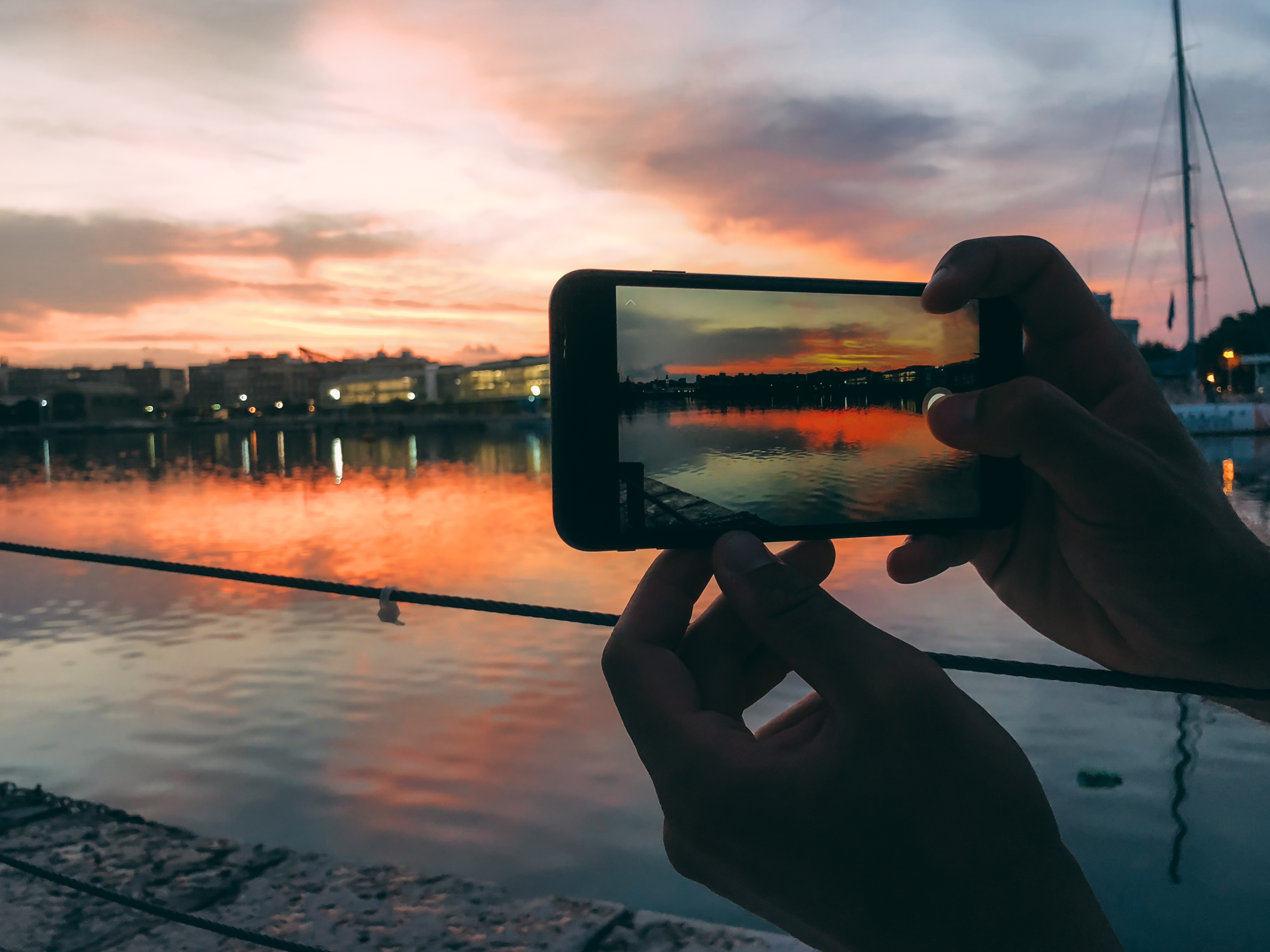 Man hands taking a picture with mobile phone of a sunset